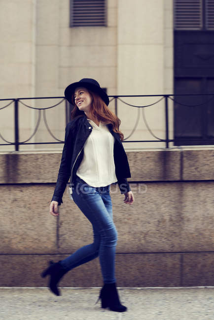 Woman in jeans and hat walking by railings — Stock Photo