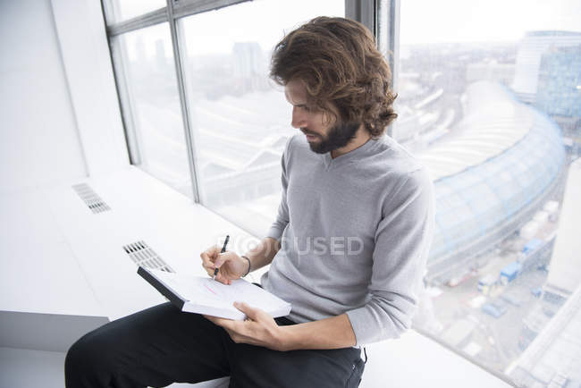 Hombre de negocios escribiendo notas en pad - foto de stock