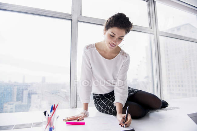 Mujer de negocios haciendo notas en almohadilla - foto de stock