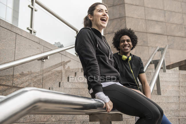 Paar lacht, während es am Geländer sitzt — Stockfoto