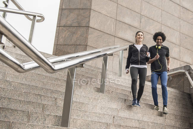 Couple jogging down stairs — Stock Photo