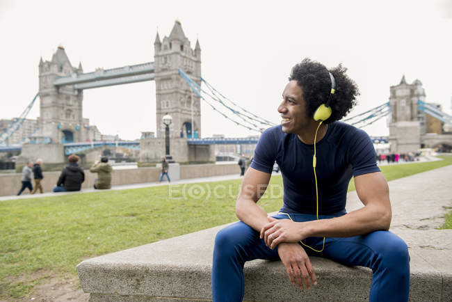 Man sitting on parapet and listening to music — Stock Photo
