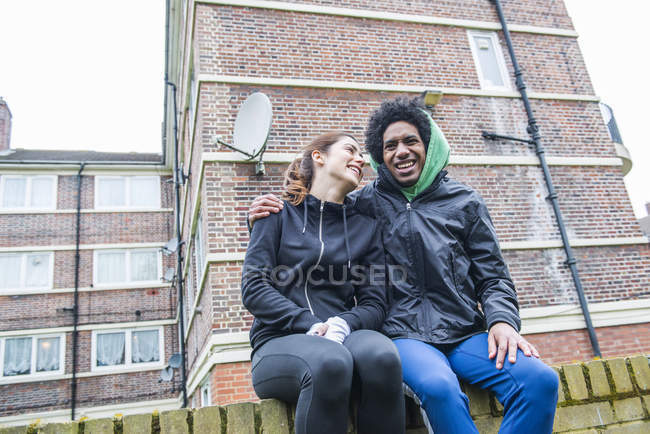 Пара, сидящая на стене вместе — стоковое фото