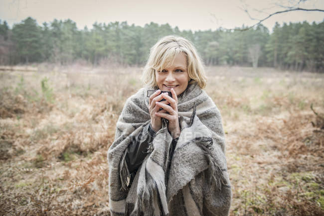Senhora envolto em cobertor apreciando xícara de chá — Fotografia de Stock