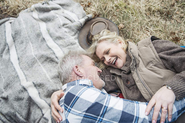 Старшая пара обнимается на одеяле — стоковое фото