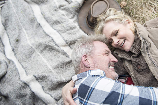 Старшая пара обнимается на одеяле — стоковое фото