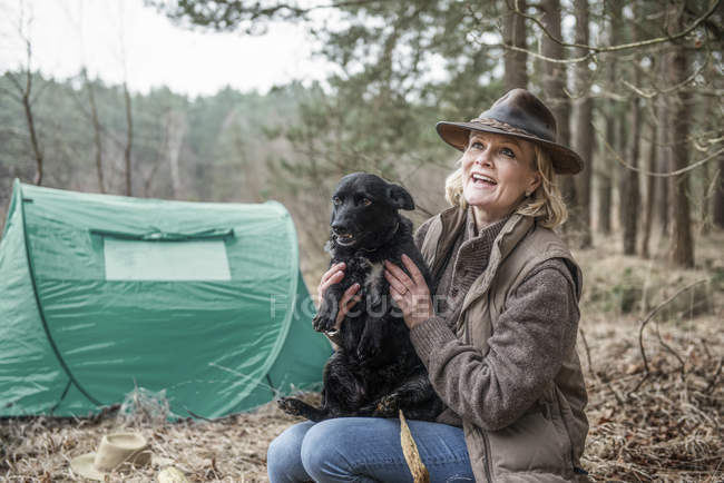 Dame sitzt mit Hund und genießt Wildnis — Stockfoto