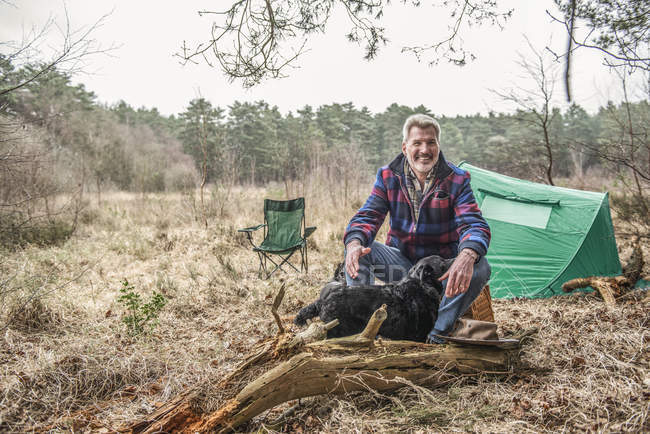 Человек, сидящий с собакой и наслаждающийся дикостью — стоковое фото