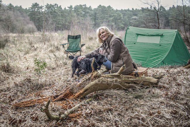 Senhora sentado com cão apreciando a natureza selvagem — Fotografia de Stock