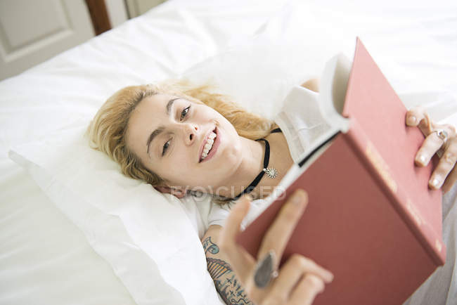 Femme couchée sur le lit lisant — Photo de stock