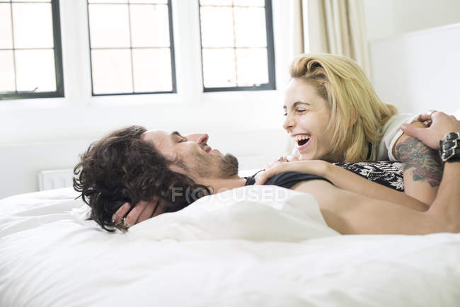 Paar liegt auf Bett und lacht zusammen — Stockfoto