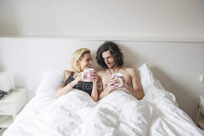 Couple couché au lit et profiter du thé — Photo de stock