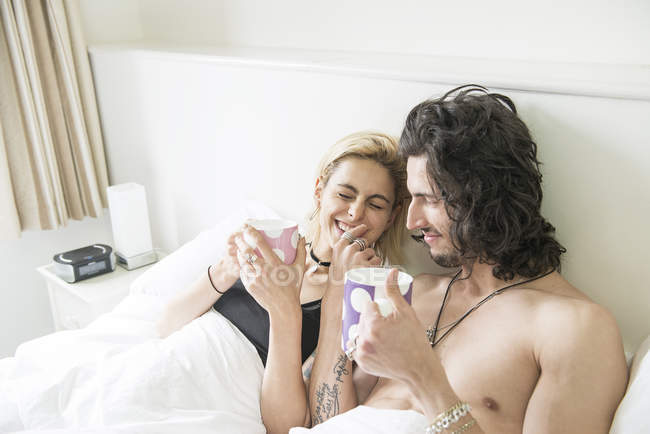 Couple lying in bed and enjoying tea — Stock Photo