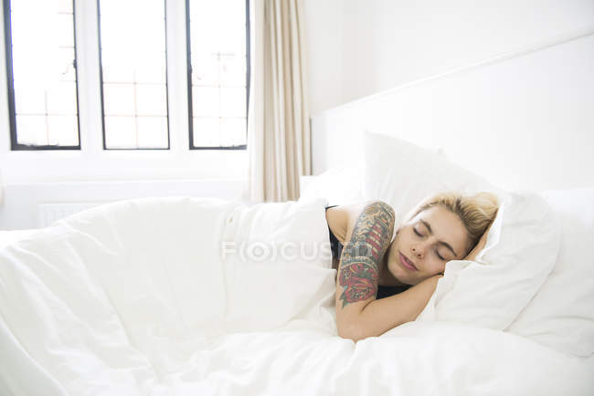 Tattooed woman asleep in bed — Stock Photo