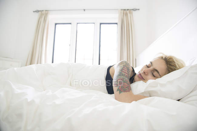 Femme tatouée endormie au lit — Photo de stock