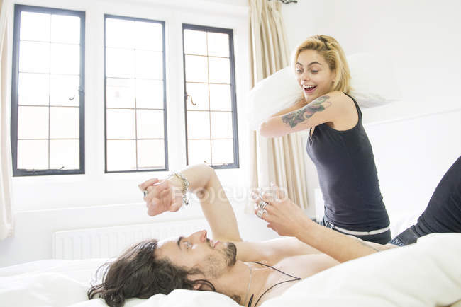 Tätowiertes Paar bei Kissenschlacht auf Bett — Stockfoto