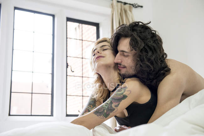 Tätowiertes Paar kuschelt auf Bett — Stockfoto