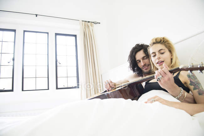 Paar liegt mit Gitarre im Bett — Stockfoto