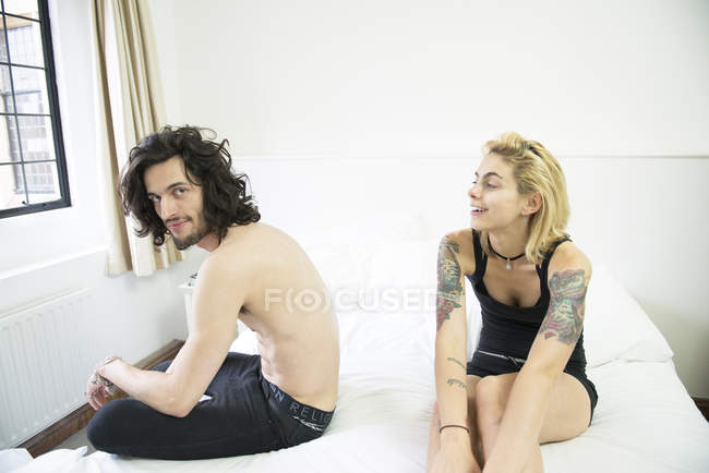 Tattooed couple sitting on bed — Stock Photo