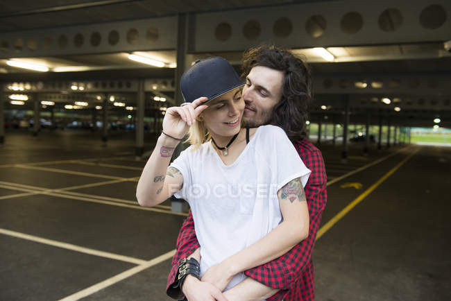 Casal abraçando uns aos outros no estacionamento — Fotografia de Stock