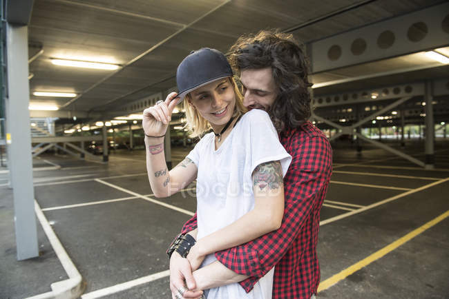 Casal abraçando uns aos outros no estacionamento — Fotografia de Stock
