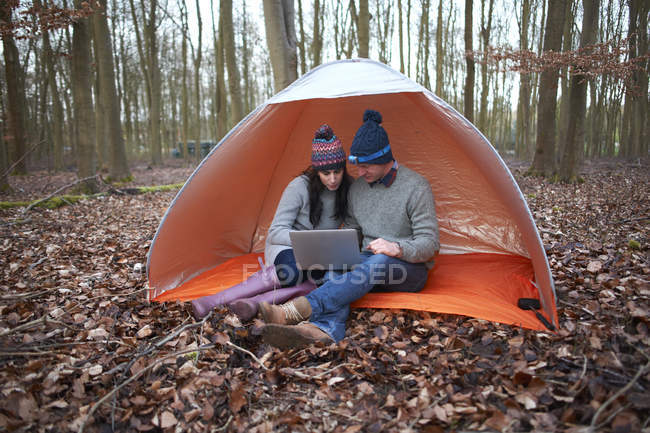 Couple sit in tent and look at laptop — Stock Photo