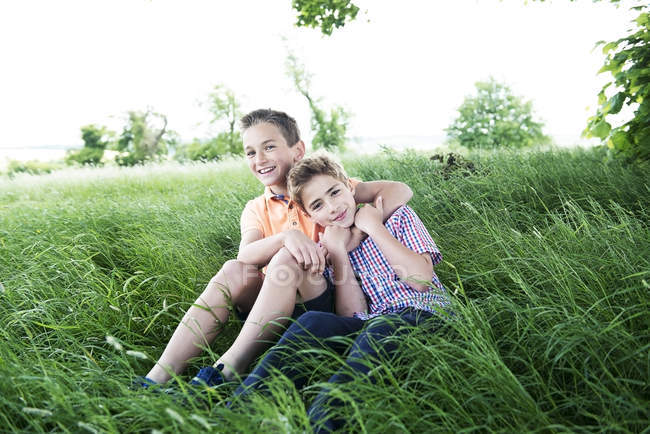 Мальчики сидят и играют в длинную траву — стоковое фото