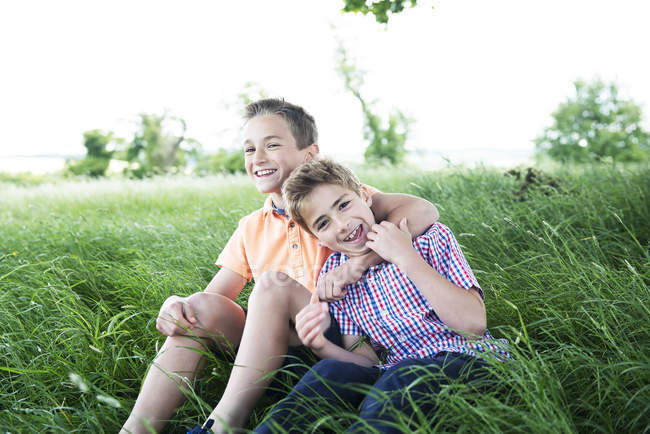 Meninos sentados e brincando em grama longa — Fotografia de Stock