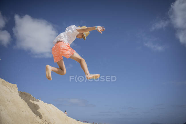 Хлопчик стрибає в піщаних дюнах на пляжі — стокове фото