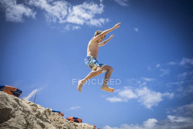 Junge springt in Sanddünen am Strand — Stockfoto