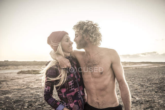 Uomo abbraccia fidanzata sulla spiaggia — Foto stock