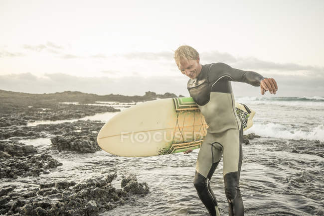 Man in wetsuit and holding surfboard — Stock Photo