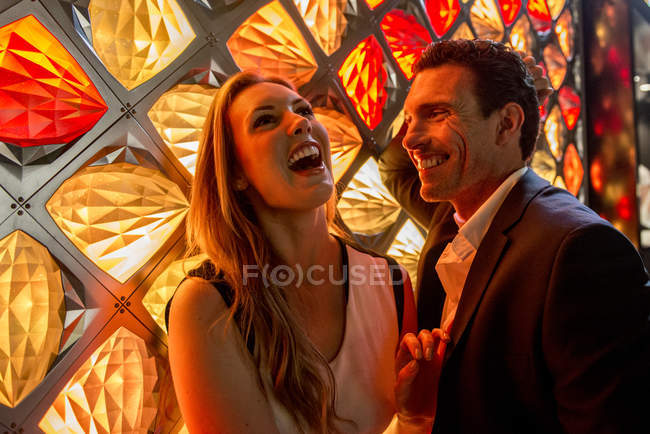 Couple laughing in front of light fixture — Stock Photo