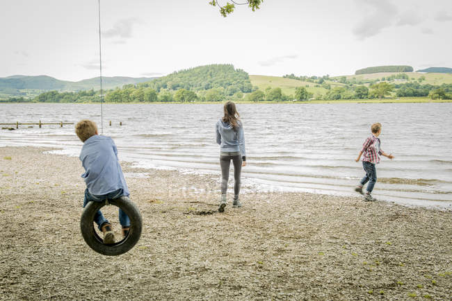 Mulher e dois meninos brincando no pneu — Fotografia de Stock