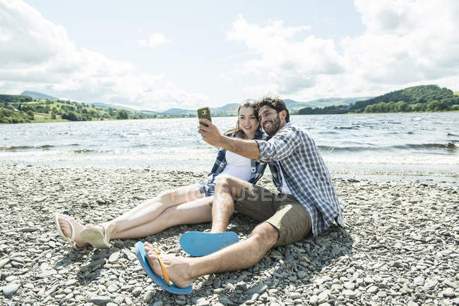 Uomo e donna scattare selfie sulla riva — Foto stock