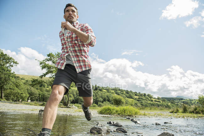 Homme traversant une rivière peu profonde — Photo de stock