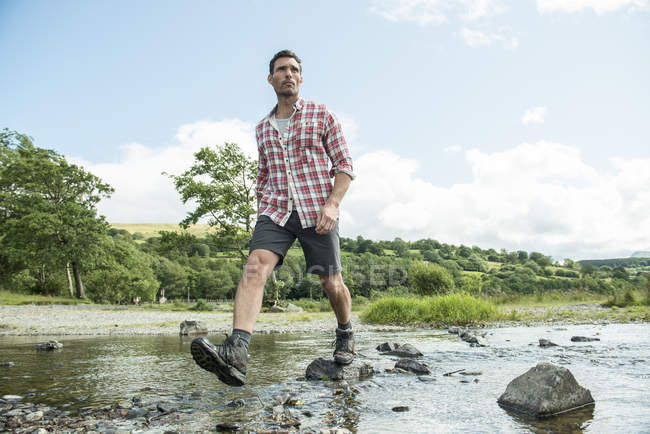 Man striding across shallow river — Stock Photo