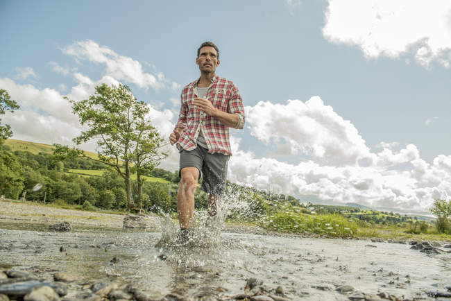 Uomo a passo di passo attraverso il fiume poco profondo — Foto stock