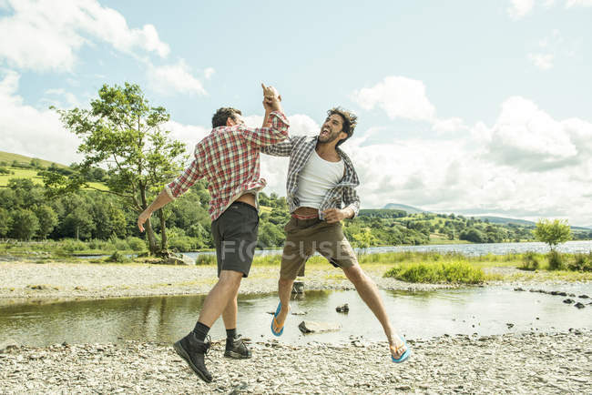 Two men leaping to high five — Stock Photo