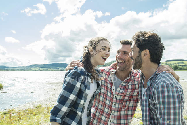 Трое друзей улыбаются на берегу — стоковое фото