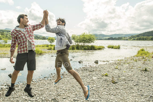 Two men leaping to high five — Stock Photo