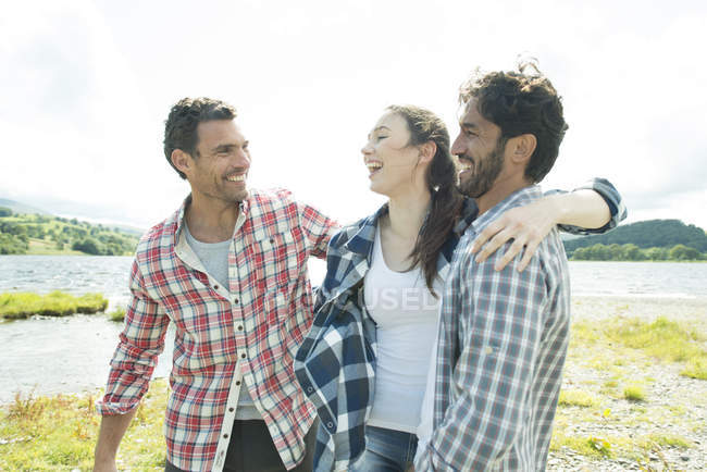 Трое друзей улыбаются на берегу — стоковое фото