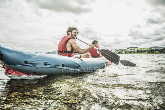 Homme et garçon en kayak pagayant loin du rivage — Photo de stock