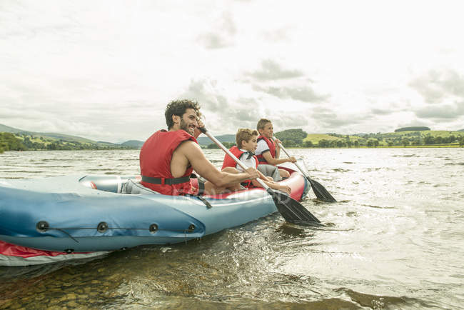 Hombre y dos chicos en kayak remando lejos - foto de stock