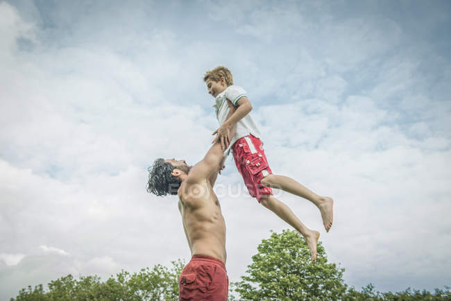 Мужчина игриво раскачивает мальчика в воздухе — стоковое фото