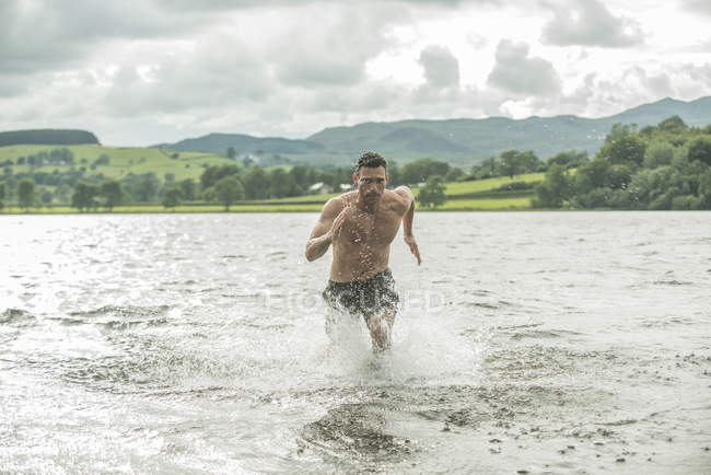 Hombre corriendo a través de aguas poco profundas - foto de stock