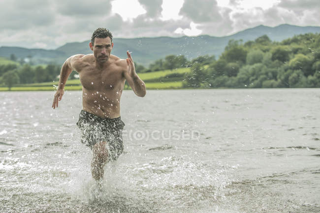 Man running through shallow water — Stock Photo