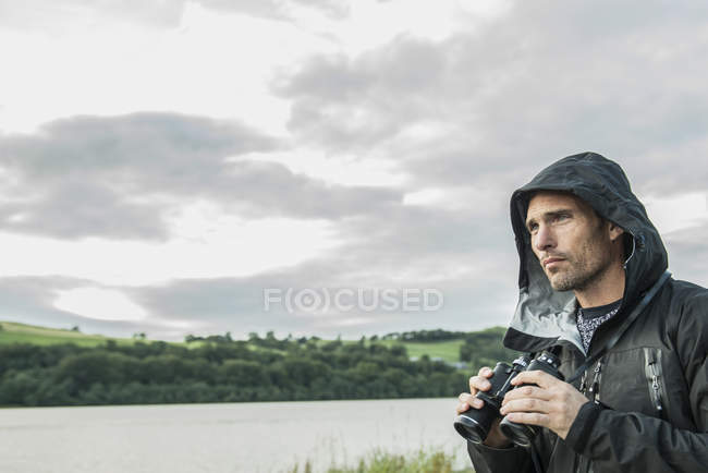 Man using binoculars on shore — Stock Photo