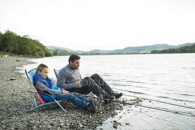 Отец и сын рыбачат с берега — стоковое фото