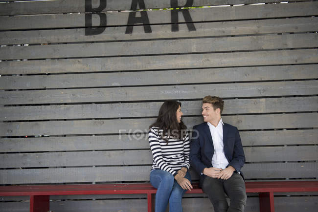 Couple sitting on bench behind bar — Stock Photo